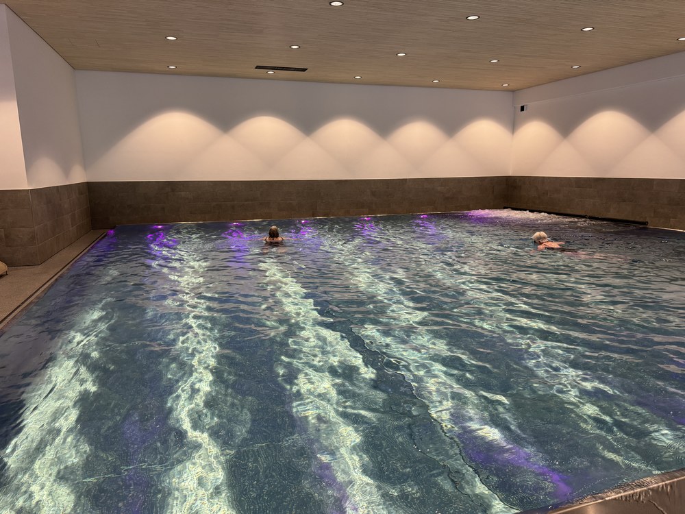 Gäste schwimmen im stimmungsvoll beleuchteten Hallenbad der Anlage